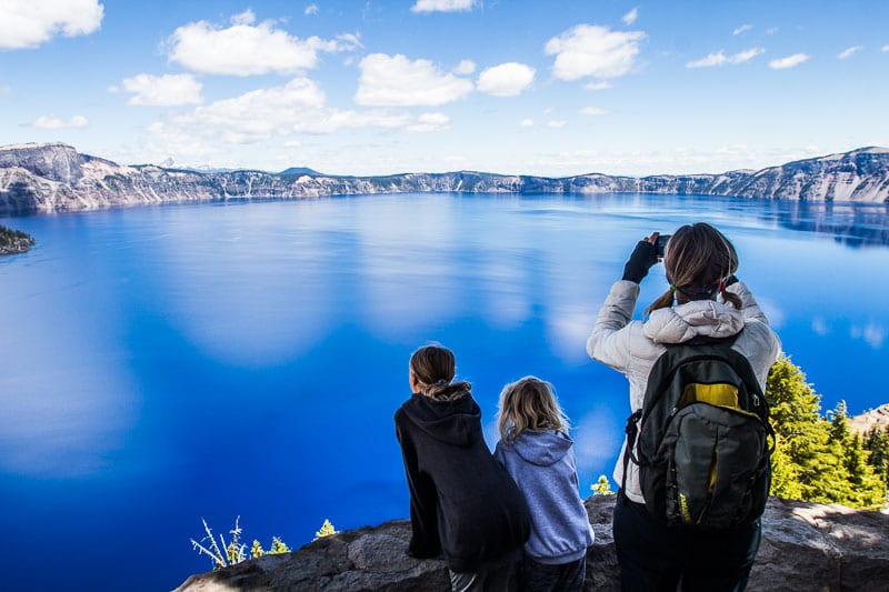 wman and girls looking at the blue waters of Crater Lake National Park, Oregon