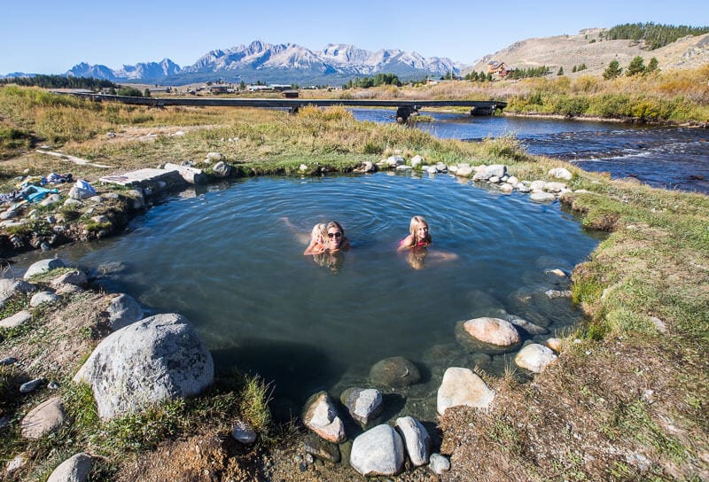 family swimming in snake pit hot springs with views of sawtooth moutnains