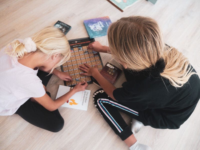 girls sitting on floor scratching off maps