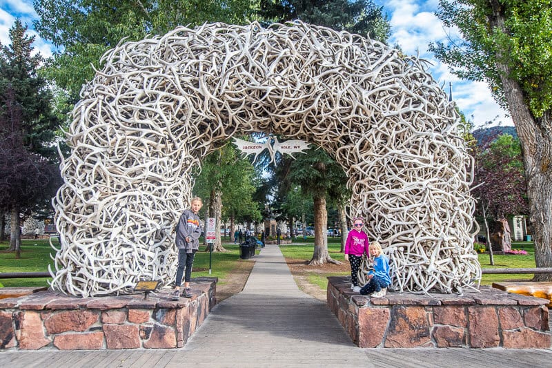 girls posing in front of arch made of horns at park entrance 