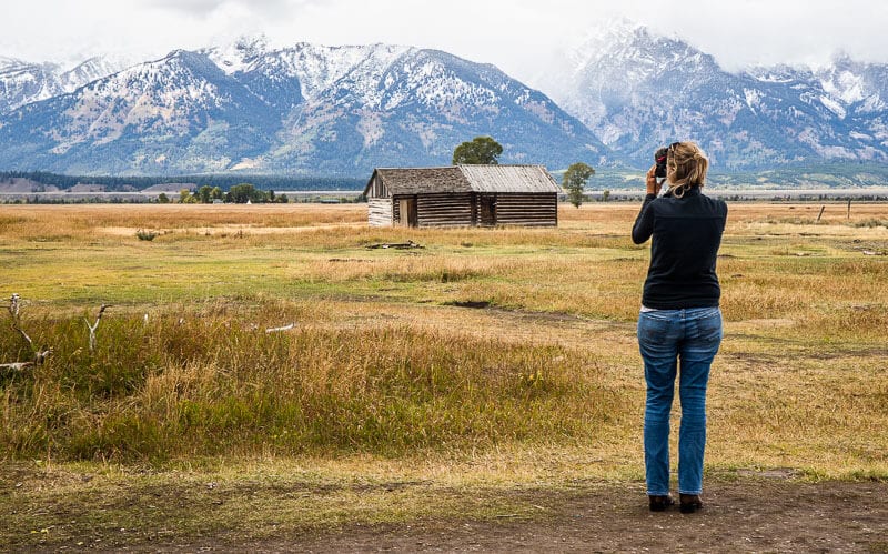 caz taking photo of wooden cabin and mountains on Mormon Row