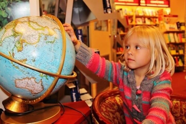 little girl looking at a globe of the world