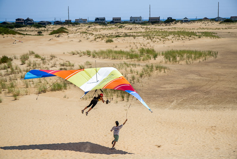 A girl hang gliding with guide on the beach