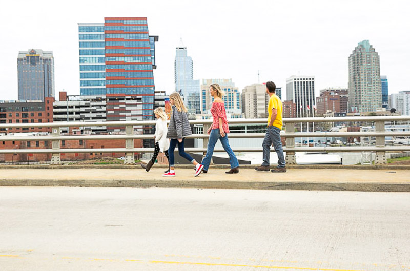 people walking across a bridge with a city in the background