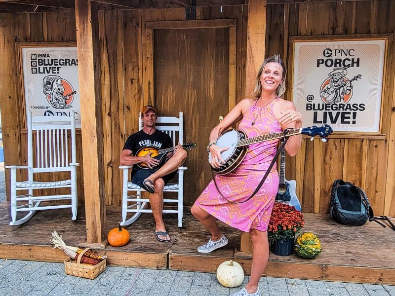 woman on banjo and man on guitar in shack
