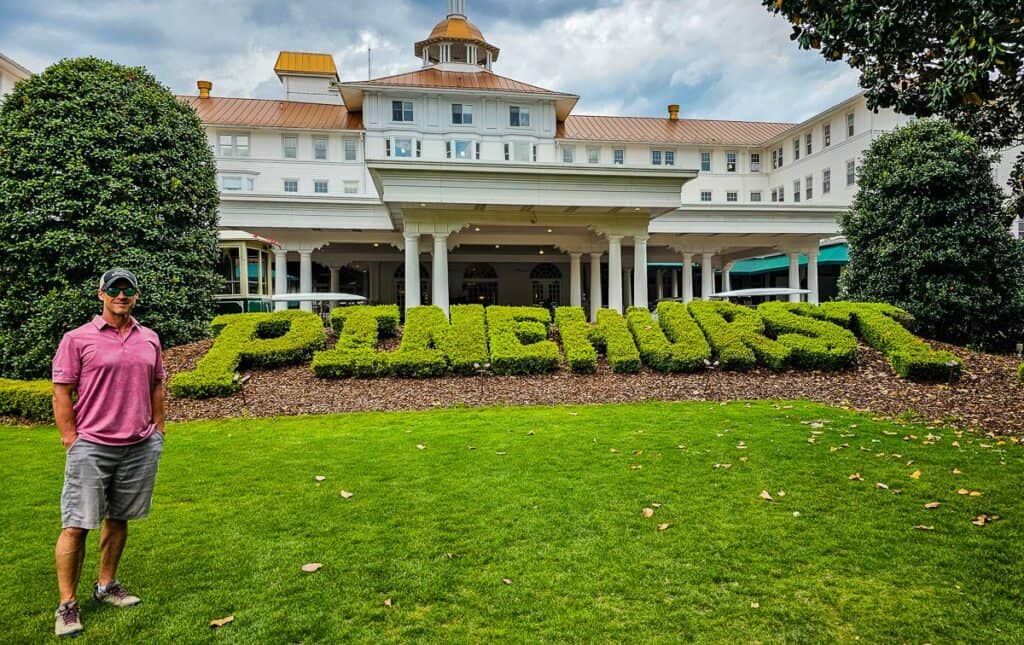 man standing outside hedge carved with words pinehurst in front of hotel