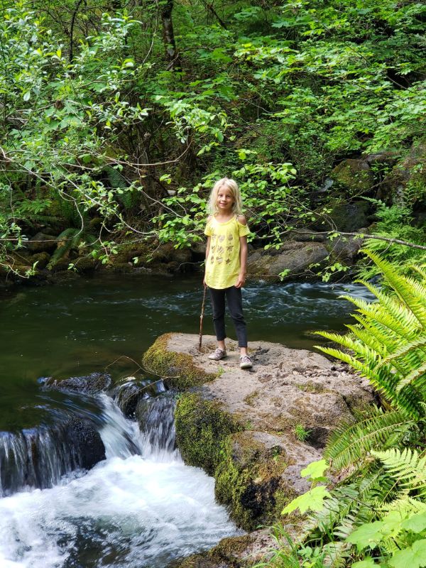 girl standing next to a small waterfall