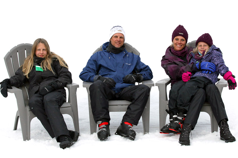 family sitting on chairs in ski clothes posing for camera