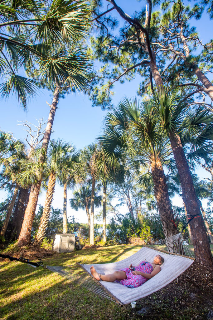 woman sitting in hammock under palm trees