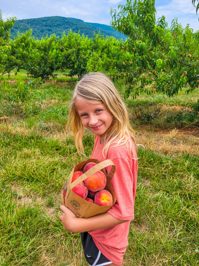 girl holding bag of peaches