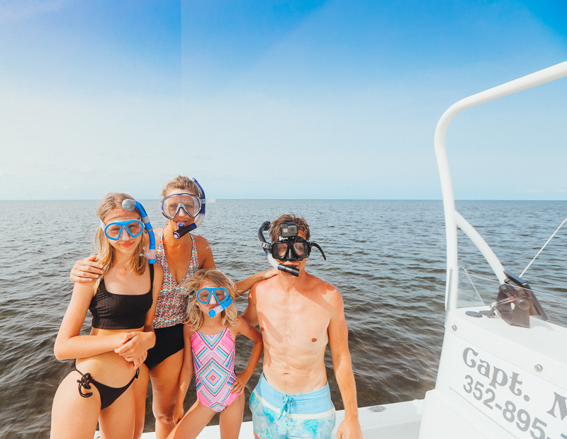 family in boat with snorkels on posing for camera
