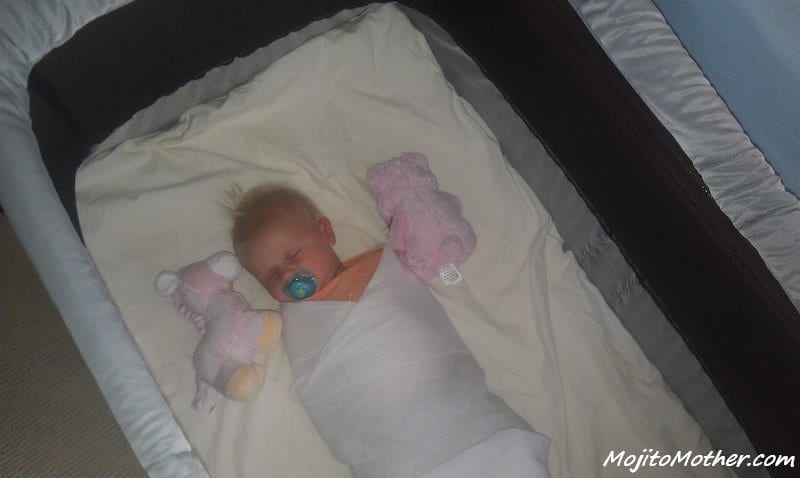 baby asleep in travel cot