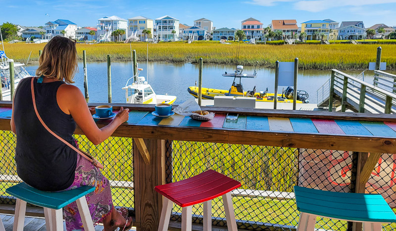 woman sitting at bench with coffee and waterway views