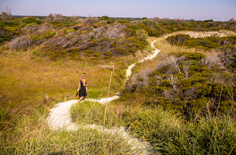 woman walking on grassy sand dunes