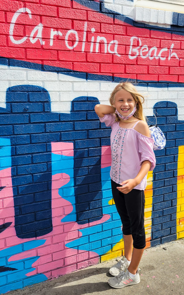 girl standing in front of a mural on a brick wall