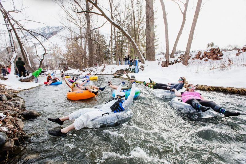 people floating down the river on tubes dressed in costumes in a snowy landscape