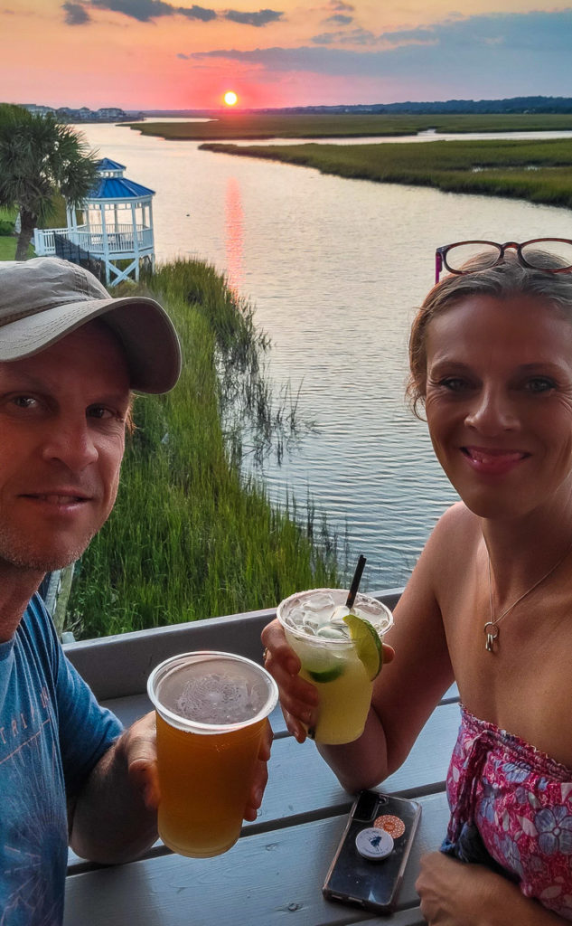 woman and man posing with drinks inf romt of jinks creek sunset