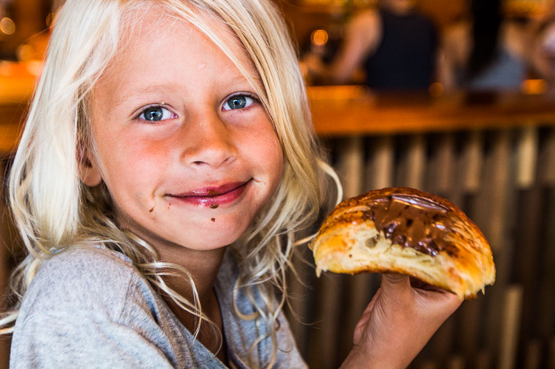 girl holding up a chocolate croissant