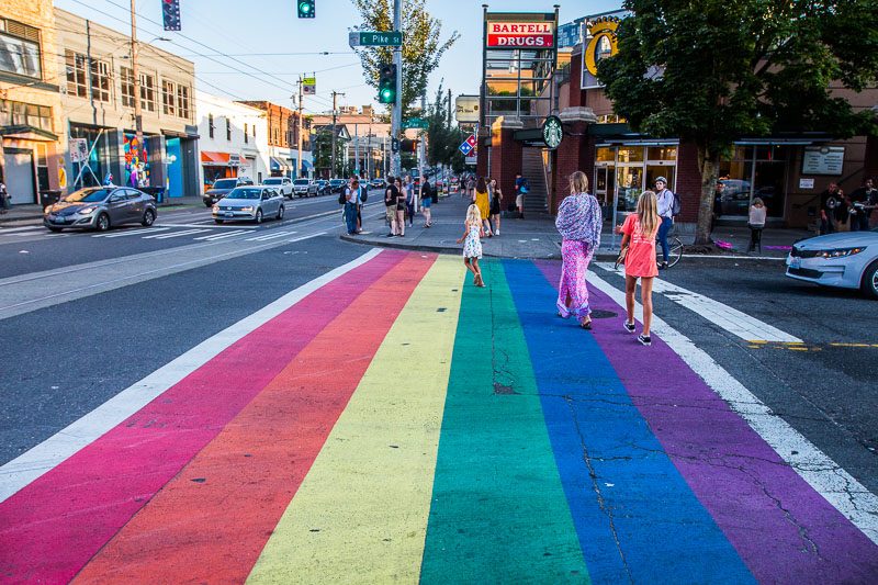 people walking across rainbow pedestrian crossing in Captil Hill Seattle
