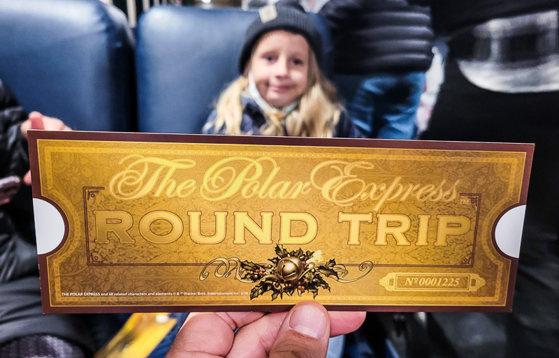 girl smiling with a Polar Express golden ticket