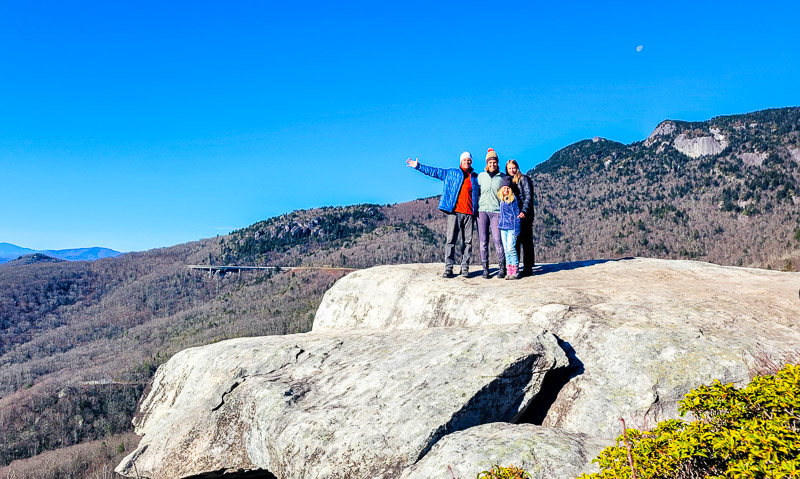 people standing on a boulder in the mountains