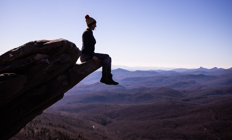 woman sitting on the edge of a boulder