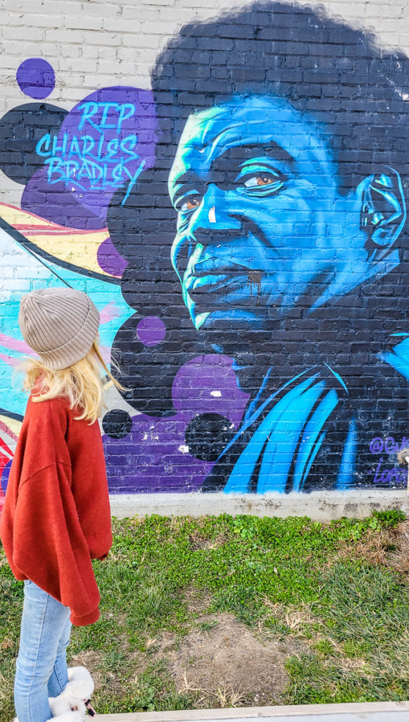 girl standing in front of a mural on a brick wall