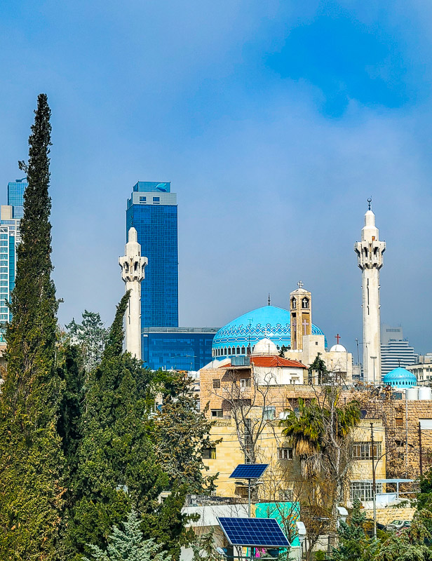 mosque with turrets and blue dome with modern skyscrapers in the background
