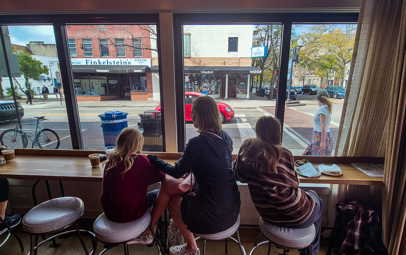 people sitting on a high table in front of a window