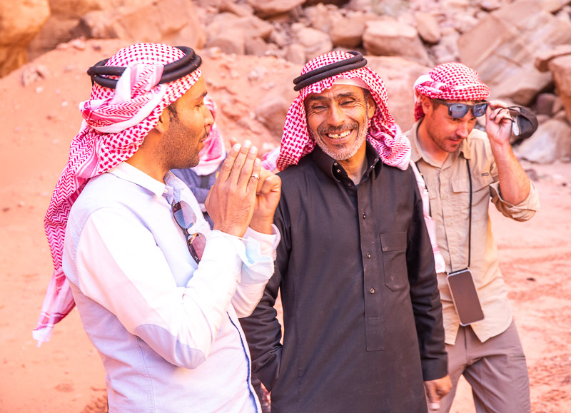 Bedouin men wearing red scarves laughing in the wAdi rum desert