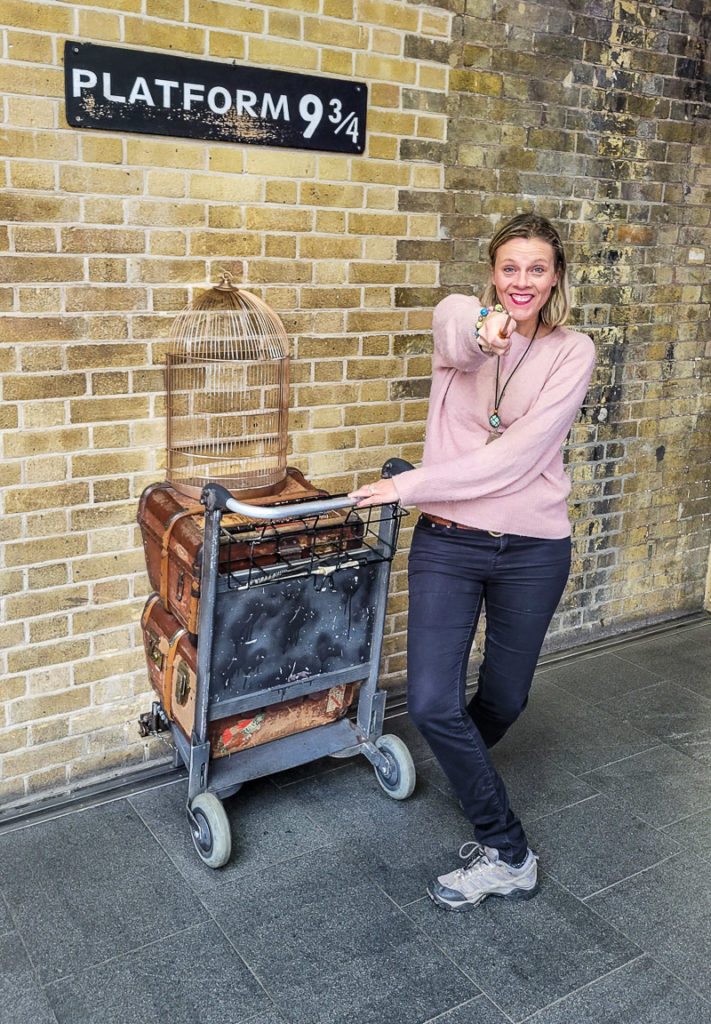woman holding wand astatine  cart going into partition  astatine  Platform 9 3/4, Kings Cross Station, London