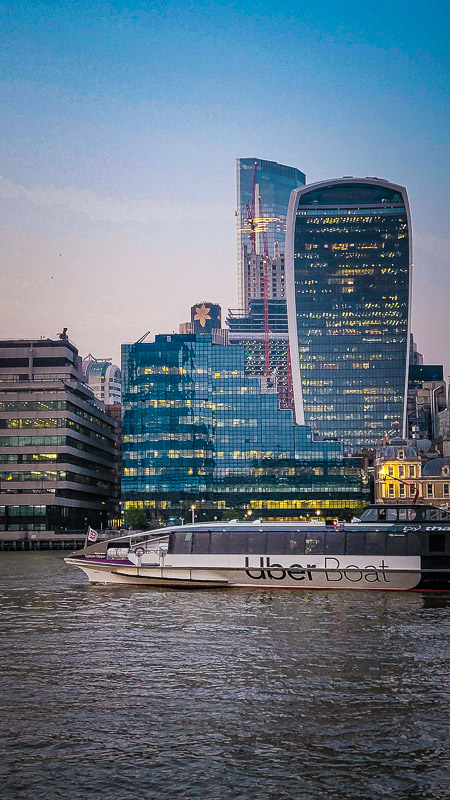 thames clipper boat going past london skyline on the thames at sunset