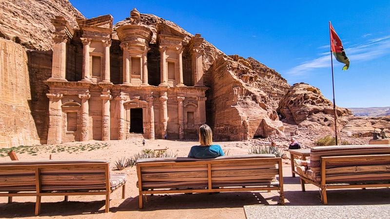 woman sitting on bench looking at ancient remains of cave building monastery cafe jordan