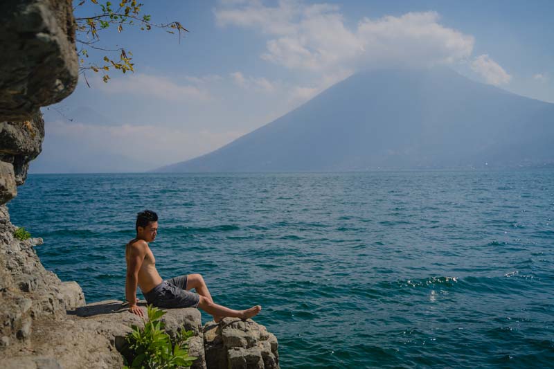 Man sitting on a rock looking out over Lake Atitlan Gautemala