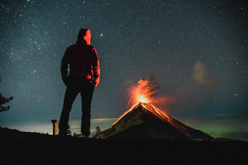 Man watching Volcano Acatenango in Guatemala erupt at night 