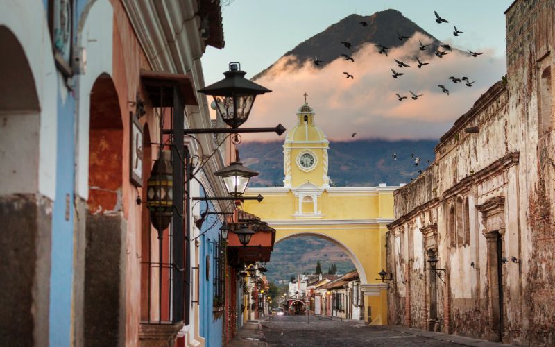 colonial buildings in antigua with volcano in background