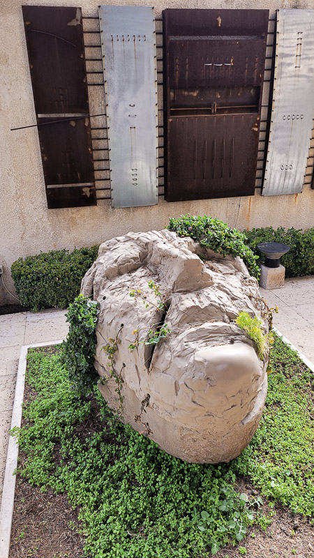 sculpture of stone face with leaves growing out of it