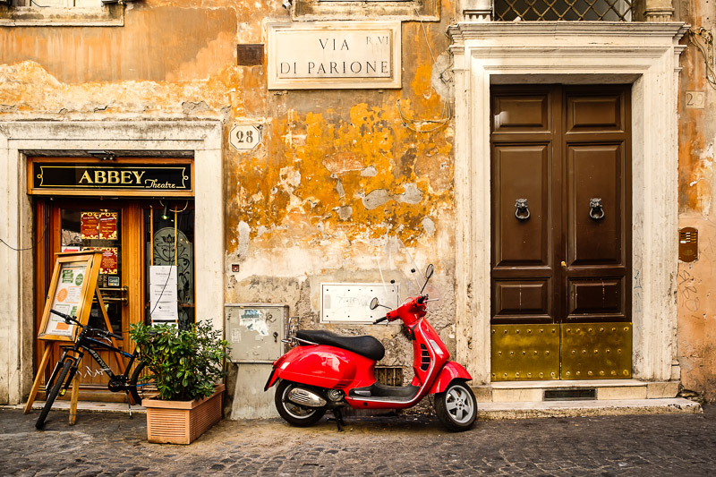 Red scooter on an old narrow cobblestoned street in Rome