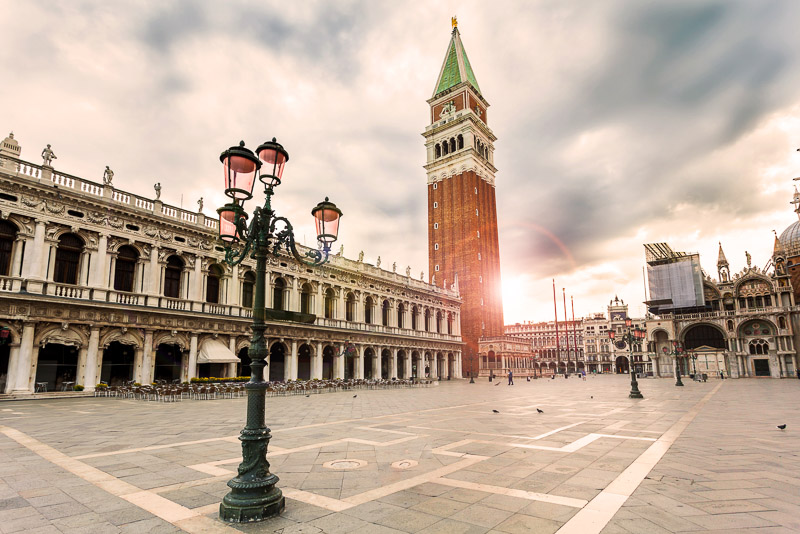 San Marco square bordered by the buildings of Campanile and Saint Mark's Basilica in sunrise. 