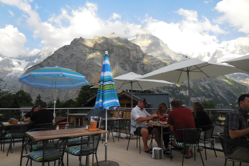 People sitting at tables at a terrace restaurant in the mountains
