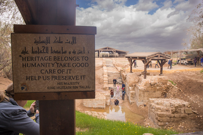 A sign with Jesus baptism site in the background