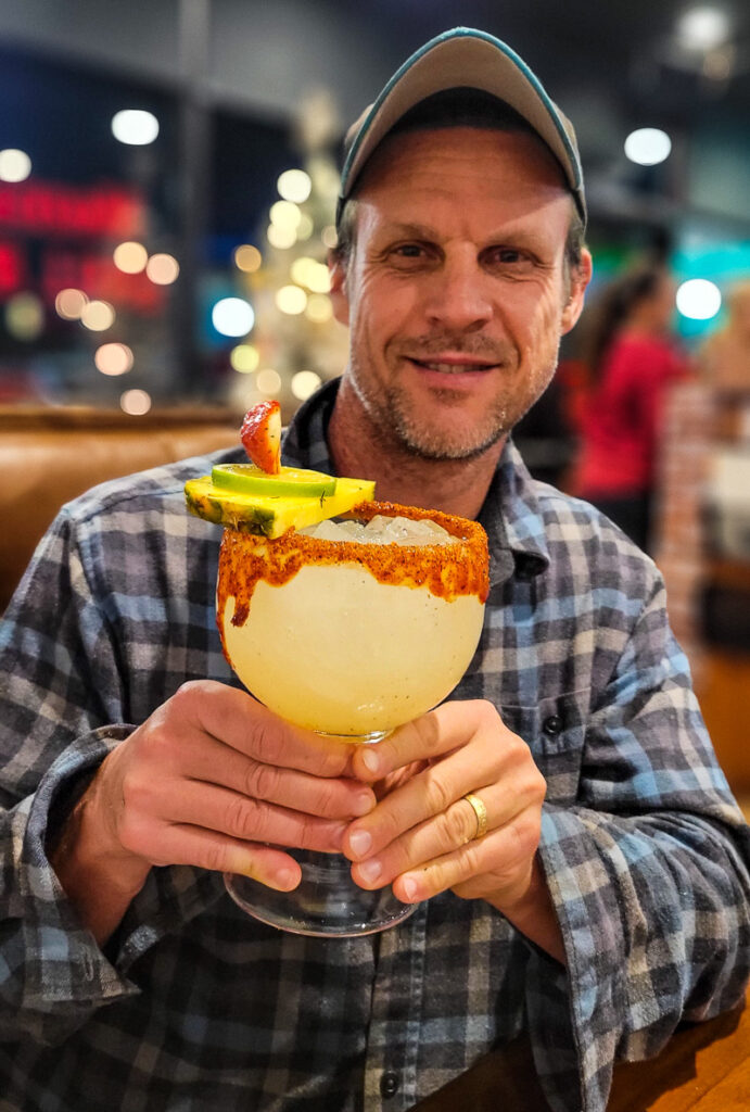 man holding a giant glass of margarita