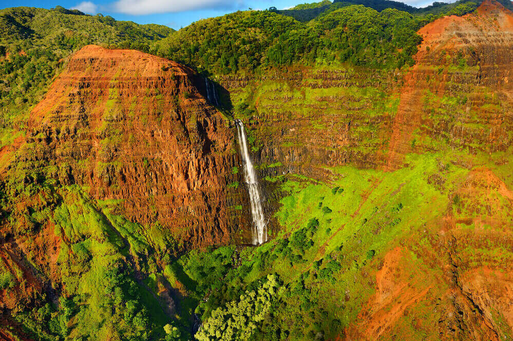waterfall spilling over the moss covered cliff faces of Waimea Canyon State PArk