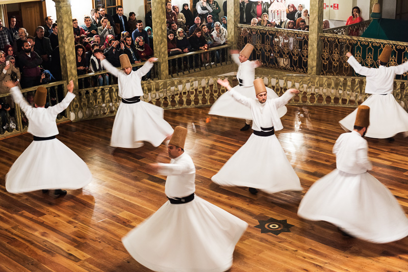 people in white dresses spinning around in a whirling dervishes ceremony