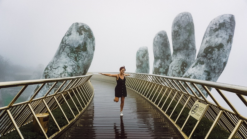 woman running on bridge between giant sculptured hands at Ba Na Hills Golden Hands Bridge