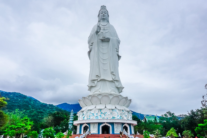 giant statue of lady buddha with green mountains in the background