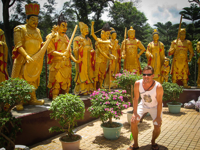 man standing in front of many gold buddha statues