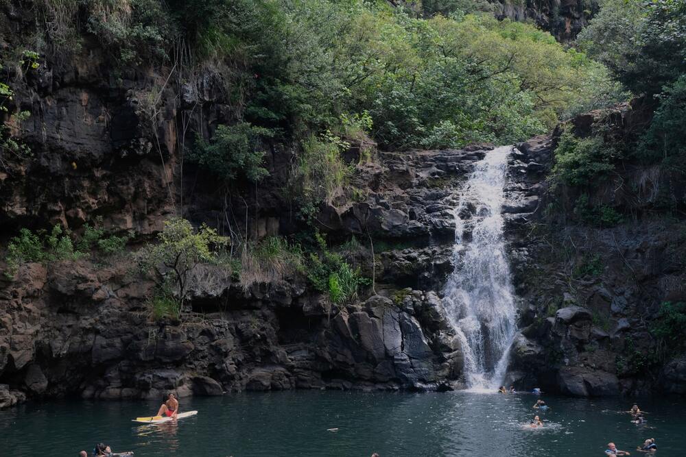 paddleboarder and simmers in the pool below a waterfall