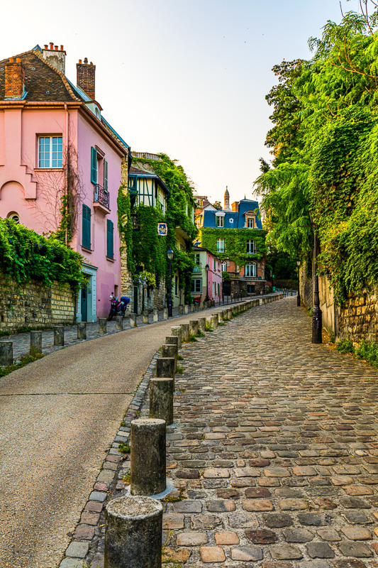 Houses on narrow road in Montmartre district of Paris. View of cozy street in quarter Montmartre in Paris, France. Architecture and landmarks of Paris. Postcard of Paris.