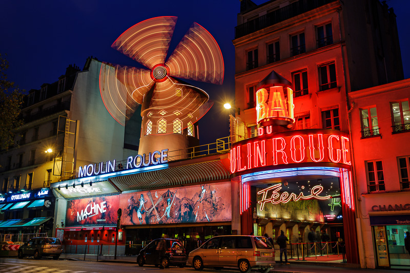 Neon lights of Moulin Rouge lit up at night with windmill spinning